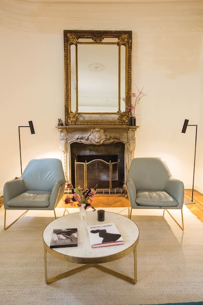 Dos sillones, coronados por dos lámparas también de Anthropologie,
custodian el antiguo hogar a leña.