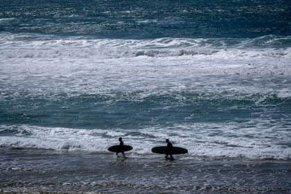 Dos surfistas en la playa en Sines, Portugal, el 1 de abril de 2024. (AP foto/Michael Probst)