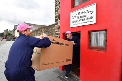 Dos trabajadores ingresan a la casa pequeña un sillón diseñado especialmente para entrar en ese espacio