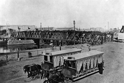 Dos tranvías a caballo frente al antiguo Puente Pueyrredón en Barracas.