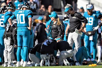 Doug Pederson, segundo desde la derecha, entrenador de los Jaguars de Jacksonville, observa el cuerpo médico del equipo atender al quarterback Trevor Lawrence después de que recibó un golpe tardío del linebacker Azeez Al-Shaair, de los Texans de Houston, durante la primera mitad del partido de la NFL del domingo 1 de diciembre de 2024, en Jacksonville, Florida. (AP Foto/Phelan M. Ebenhack)