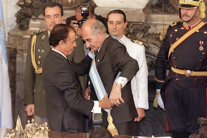 Carlos Menem le coloca la banda presidencial a Fernando de la Rúa