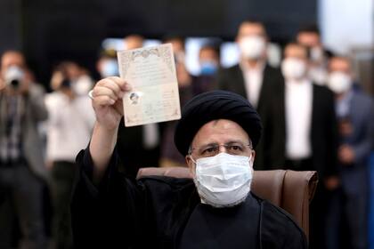 Ebrahim Raisi, jefe del poder judicial iraní, muestra su documento de identidad mientras se registra como candidato para las elecciones presidenciales del 18 de junio, en la sede del Ministerio del Interior, en Teherán, Irán, el 15 de mayo de 2021. (AP Foto/Ebrahim Noroozi)