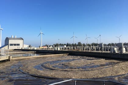 La mayor planta de tratamiento del agua en Copenhague y, detrás, molinos eólicos