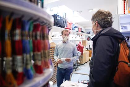 El 4 de mayo, el propietario de una mercería en Bruselas atiende a un cliente, ya que las tiendas en una calle comercial de la capital belga abrieron sus puertas el primer día del levantamiento parcial de las restricciones para intentar detener la propagación del coronavirus