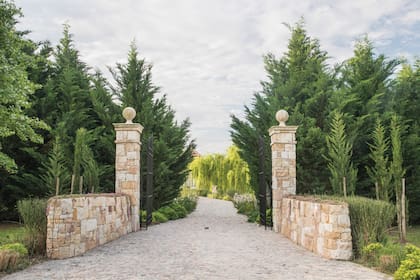 El acceso a la propiedad se realiza a través de un portón de hierro con muretes y columnas de piedra, en donde ya se vislumbra el estilo de La Toscana.