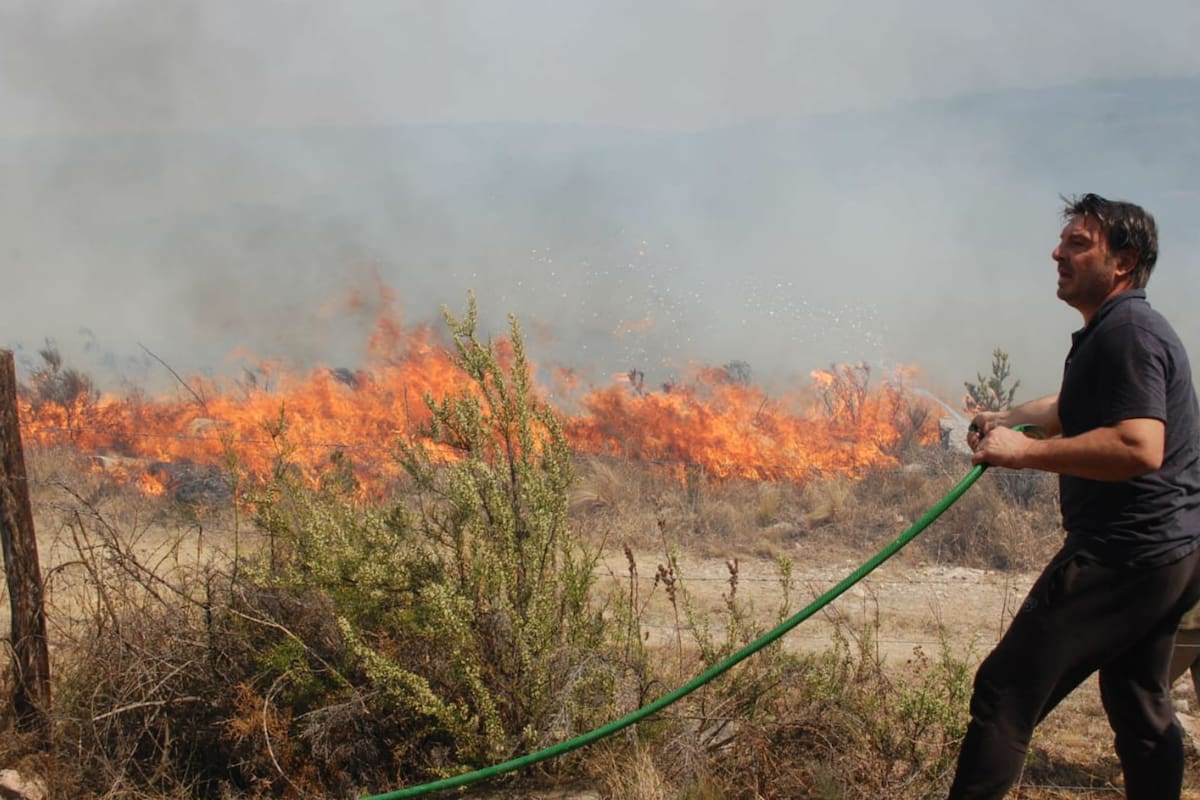 El actor intentando combatir el fuego, mientras avanza hacia el complejo de cabañas que tiene en Villa Giardino