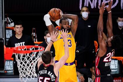 El alero de Los Angeles Lakers, LeBron James, pasa entre el escolta del Miami Heat, Duncan Robinson, a la izquierda, y el alero Jimmy Butler durante la segunda mitad del Juego 4 de las Finales de la NBA, el martes 6 de octubre de 2020, en Lake Buena Vista, Florida.