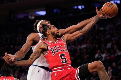 El alero de los Bulls de Chicago Derrick Johns Jr. disputa un rebote con el pívot de los Knicks de Nueva York Mitchell Robinson en la primera mitad del juego del jueves 2 de diciembre de 2021, en Nueva York. (AP Foto/Mary Altaffer)