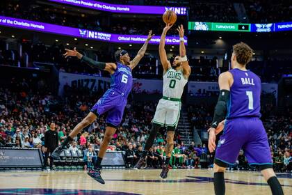 El alero de los Celtics de Boston Jayson Tatum lanza el balón sobre el alero de los Hornets de Charlotte Jalen McDaniels en el encuentro del sábado 14 de enero del 2023. (AP Foto/Scott Kinser)