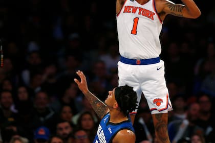 El alero de los Knicks de Nueva York Obi Toppin clava el balón sobre el alero del Magic de Orlando Paolo Banchero el lunes 24 de octubre del 2022. (AP Foto/John Munson)