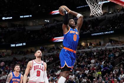 El alero de los Knicks de Nueva York OG Anunoby salta para clavar el balón mientras lo observa el pívot de los Bulls de Chicago Nikola Vucevic en el encuentro de la NBA del martes 9 de abril del 2024. (AP Foto/Nam Y. Huh)