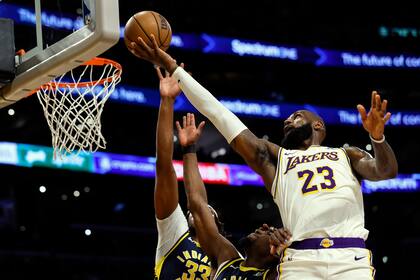 El alero de los Lakers de Los Ángeles LeBron James lanza el balón sobre el pívot de los Pacers de Indiana Myles Turner y el alero Aaron Nesmith en el encuentro del domingo 24 de marzo del 2024. (AP Foto/Etienne Laurent)