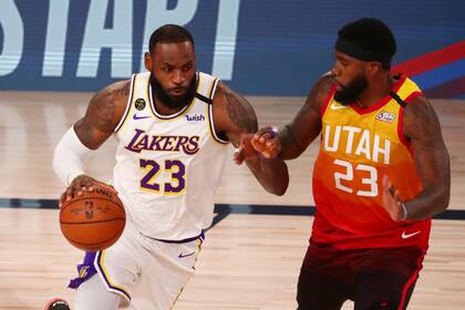 El alero de los Lakers de Los Ángeles, LeBron James, a la izquierda, dribla contra el alero de los Jazz de Utah, Royce ONeale, a la derecha, durante la primera mitad de un partido de baloncesto de la NBA el lunes 3 de agosto de 2020