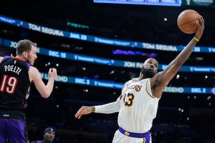 El alero de los Lakers de Los Ángeles LeBron James recupera un rebote frente al pívot de los Raptors de Toronto Jakob Poeltl en el encuentro del domingo 10 de noviembre del 2024. (AP Foto/Marcio Jose Sanchez)