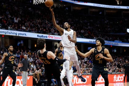 El alero de los Nets de Brooklyn Kevin Durant lanza el balón superando al alero Cedi Osman y el pívot Jarrett Allen de los Cavaliers de Cleveland en el encuentro del lunes 26 de diciembre del 2022. (AP Foto/Ron Schwane)