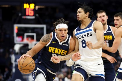 El alero de los Nuggets de Denver, Aaron Gordon, a la izquierda, pasa junto al alero de los Timberwolves de Minnesota, Josh Minott (8), durante la segunda mitad de un partido de pretemporada de baloncesto de la NBA, el jueves 17 de octubre de 2024, en Minneapolis. (AP Foto/Matt Krohn)