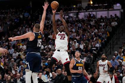 El alero del Heat de Miami Jimmy Butler lanza el balón frente al pívot de los Nuggets de Denver Nikola Jokic