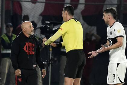 El árbitro colombiano Wilmar Roldán le pide calma a Jorge Sampaoli, técnico de Flamengo, que discute con Alejandro Silva, de Olimpia