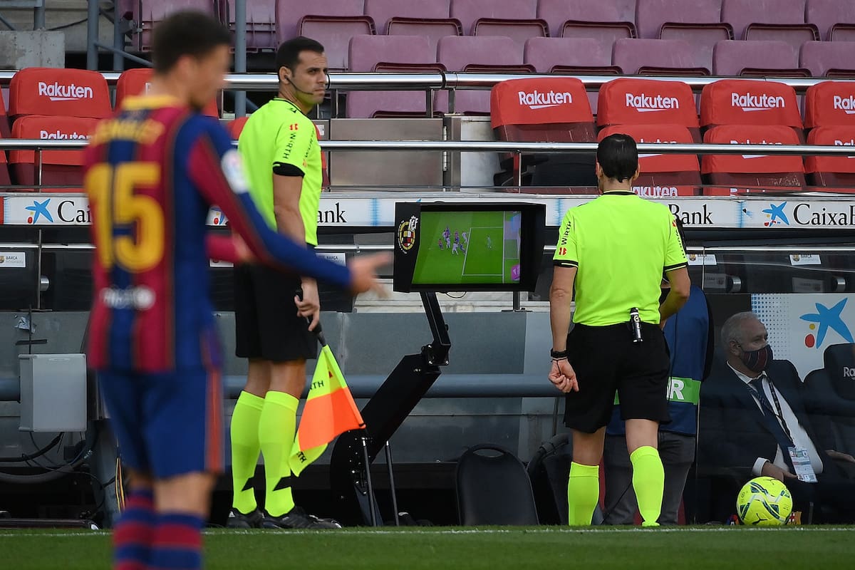 El árbitro español Juan Martínez Munuera (R) revisa el VAR por un penalti durante el partido de fútbol de la Liga española entre Barcelona y Real Madrid