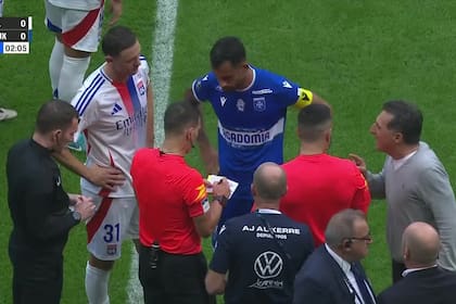 El árbitro Jeremy Stinat firma la solicitud del reclamo de Auxerre luego del empate ante Lyon 2-2. El equipo visitante amenazó con retirarse del campo por un penal cobrado por el VAR; a la derecha, el DT Christophe Pelissier