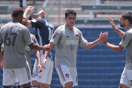 El argentino Cristian Pavón se saluda con sus compañeros durante un entrenamiento de Los Ángeles Galaxy; el lunes, los angelinos se medirán con Portland, en Orlando