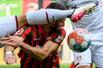 El argentino Exequiel Palacios, de Leverkusen, disputa un balón con Daniel Caligiuri, de Augsburg, en partido por la Bundesliga jugado en Augsburgo, Alemania, sábado 28 de agosto de 2021. Leverkusen ganó 4-1. (Matthias Balk/dpa via AP)
