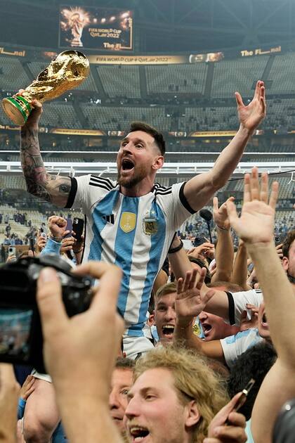 El argentino Lionel Messi celebra con el trofeo ante los hinchas tras ganar el Mundial en la final entre Argentina y Francia en el estadio Lusail