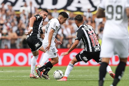 El argentino Thiago Almada maniobra ante la marca de dos jugadores de Mineiro