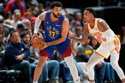 El armador de los Nuggets de Denver Jamal Murray (27) busca a quien pasar la bola mientras es defendido por el base de los Hawks de Atlanta Dejounte Murray durante la primera mitad del juego de baloncesto de la NBA, el sábado 6 de abril de 2024, en Denver. (AP Foto/David Zalubowski)
