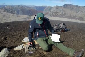 El arqueólogo Emmanuel Vargas, junto a la placa que data de 1890 en el Cerro Pantojo, cerca del paso Cardenal Samoré
