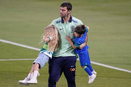 El arquero brasileño Alisson juega con su hija Helena y su hijo Matteo tras un entrenamiento, el martes 29 de noviembre de 2022, en Doha, Qatar. Brasil enfrentará a Camerún el viernes en el Mundial. (AP Foto/Andre Penner)