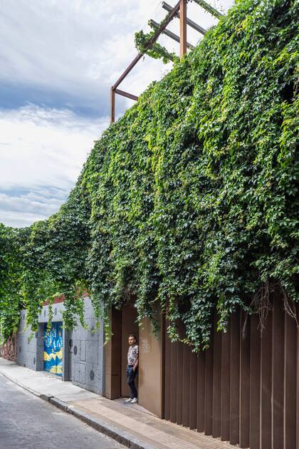 El arquitecto Juan Pinilla posa en la fachada de la propiedad integrada al paisaje barrial con el mural, la enredadera y el portón de hierro.