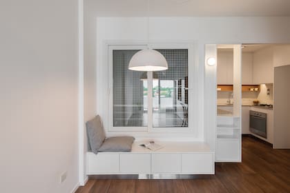 El asiento con cajones para marca el lugar del comedor. Como transición, un módulo tapa la cabecera de la mesada y, siguiendo la idea principal, agrega espacio de guardado con un botinero.