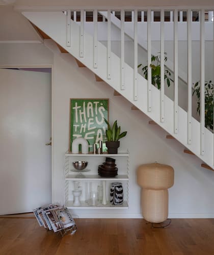 El bajo escalera, aprovechado como rincón deco. Impresión de la neerlandesa (Anouk van Cleef por The Poster Club), lámpara (Ferm Living), jarrón de dos colores (Hay Design). Revistero metálico vintage.