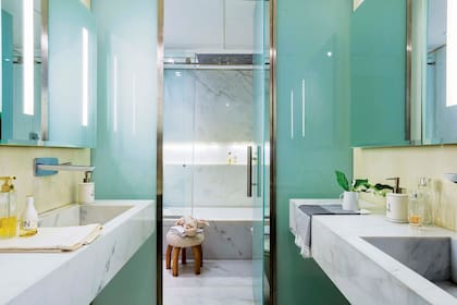 El baño de la suite tiene mesadas y revestimiento de mármol (Oscar Revestimientos), grifería cromada (Hansgrohe) y mampara de vidrio (Centro Cristales).