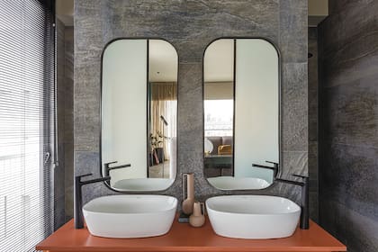 El baño está revestido en porcelanato (Cerámica San Lorenzo) con mesada de Silestone 'Arcilla Red' (Canteras del Mundo), bachas 'Tori' (Ferrum) y canilla 'Epuyén' negra (FV).