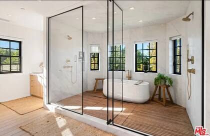 El baño principal, de estilo spa, está equipado con ducha con mampara de vidrio y acabados de alta gama