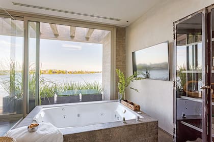 El baño principal tiene una tele, revestimientos de porcelanato ‘La Roche Mud’ (SBG). Mueble tipo farmacia antigua (estudio Shilton-Stefani Arquitectos).