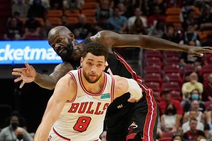El base de los Bulls de Chicago Zach LaVine maneja el balón afuera del pivot del Heat de Miami  Dewayne Dedmon en el encuentro del sábado 11 de diciembre del 2021. (AP Photo/Marta Lavandier)