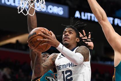 El base de los Grizzlies de Memphis Ja Morant salta hacia la canasta superando al pívot de los Pistons de Detroit Jalen Duren en el encuentro del domingo 4 de diciembre del 2022. (AP Foto/Jose Juarez)