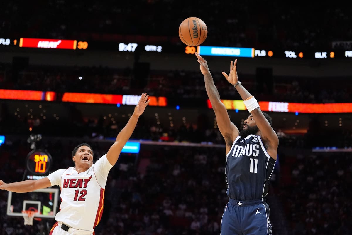 El base de los Mavericks de Dallas Kyrie Irving lanza el balón sobre el base del Heat de Miami Dru S