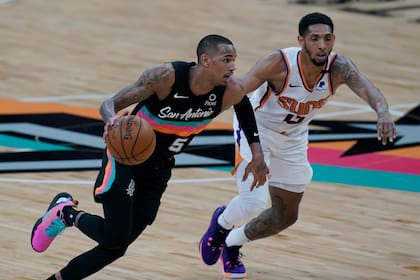 El base de los Spurs de San Antonio Dejounte Murray avanza hacia la canasta mientras lo defiende Cameron Payne de los Suns de Phoenix en el encuentro del domingo 16 de mayo del 2021. (AP Photo/Eric Gay)