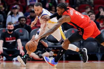 El base de los Warriors de Golden State Stephen Curry y el base de los Rockets de Houston Kevin Porter Jr. luchan por el balón durante la primera mitad del partido de la NBA, el lunes 31 de enero de 2022, en Houston. (AP Foto/Michael Wyke)