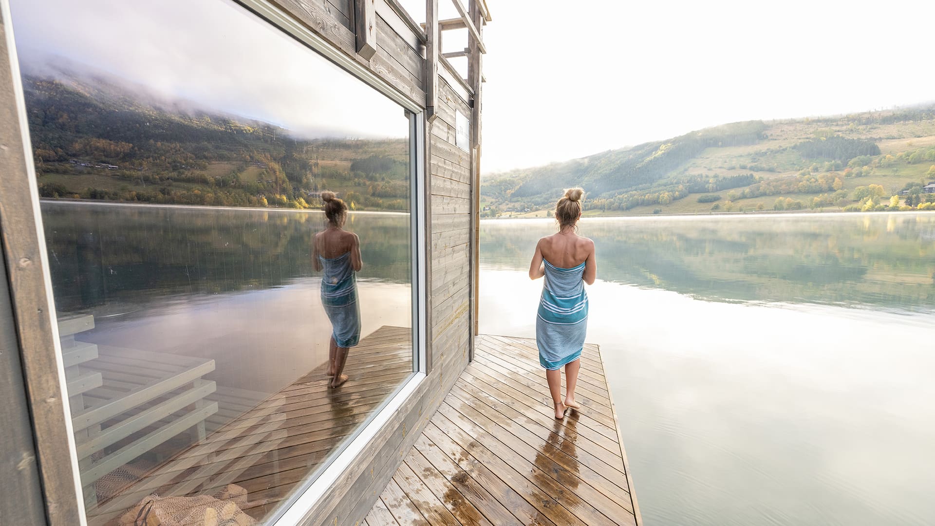 Young woman relaxing outside a in floating sauna, she contemplates nature
