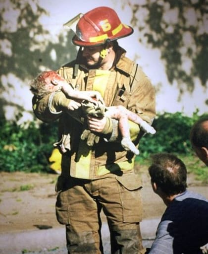 El bombero Chris Fields sosteniendo en sus brazos a Baylee Almon, una niña de un año gravemente herida en el ataque (Charles Porter IV distributed by Associated Press)
