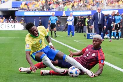 El brasileño Vinicius Júnior (izquierda) tras la barrida del costarricense Jeyland Mitchell en el partido por el Grupo D de la Copa América, el lunes 24 de junio de 2024, en Inglewood, California. (AP Foto/Mark J. Terrill)