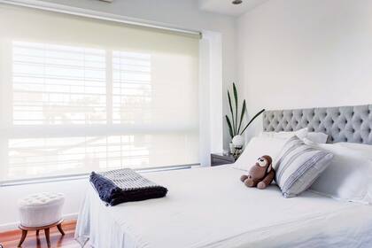 El cabezal de lino capitoné, el cubrecama, los almohadones y un banquito vintage retapizado (todo de Estévez) bastan para crean un clima de calma en el dormitorio principal.