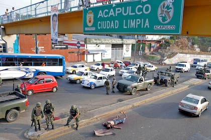 El cadáver de un hombre que colgaba de un puente peatonal antes de que la cuerda se desprendiera es custodiado por soldados mexicanos en Acapulco, México.