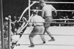 El campeón de peso pesado Jack Dempsey se cae del ring después de ser empujado contra las cuerdas por el argentino Luis Firpo en el primer asalto de su pelea por el título de 1923 en el antiguo Polo Grounds